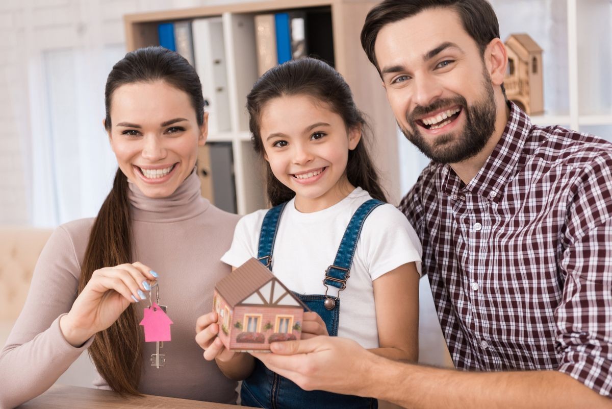 Young family is happy to buy new house, holding keys from house and miniature house. Buying a property. Concept of real estate sales.